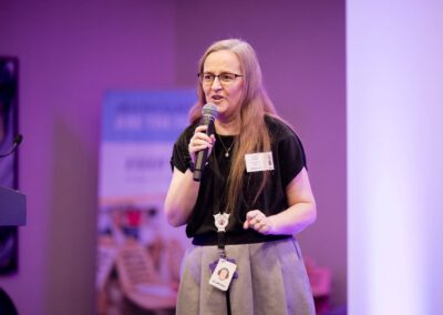 Abigail Hawkins FCCT talking on the stage at SENsible24 SENCO Conference. Community Playthings banner is in the background.
