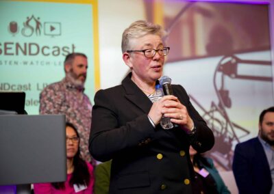Dr Susie Nyman with the microphone taking questions from the audience. and a background of SENDcast live